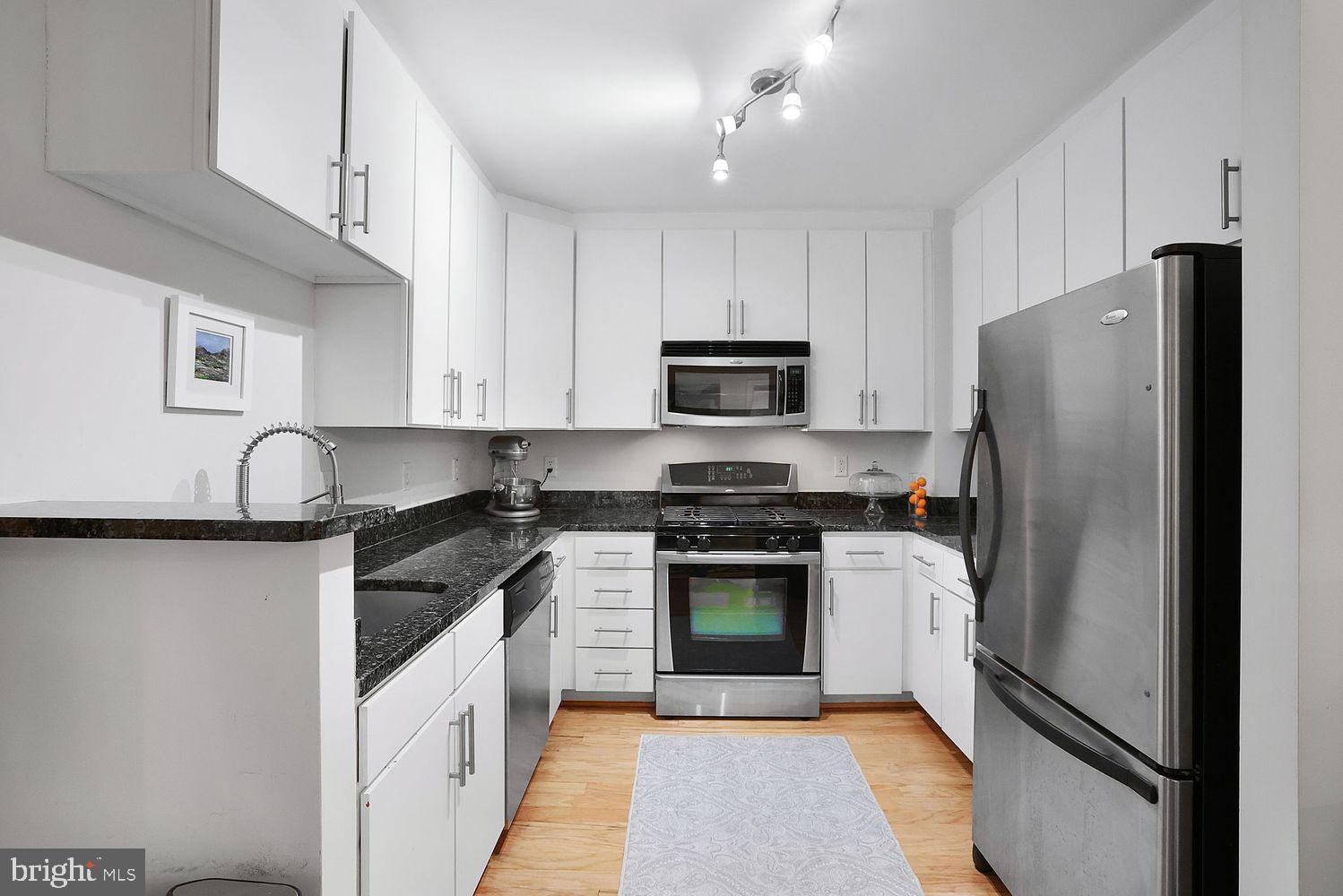 915 E Street Northwest, Unit 403 Washington, DC 20004 - Photo 9 of 30 a kitchen with stainless steel appliances granite countertop a stove a refrigerator and a sink with wooden floor