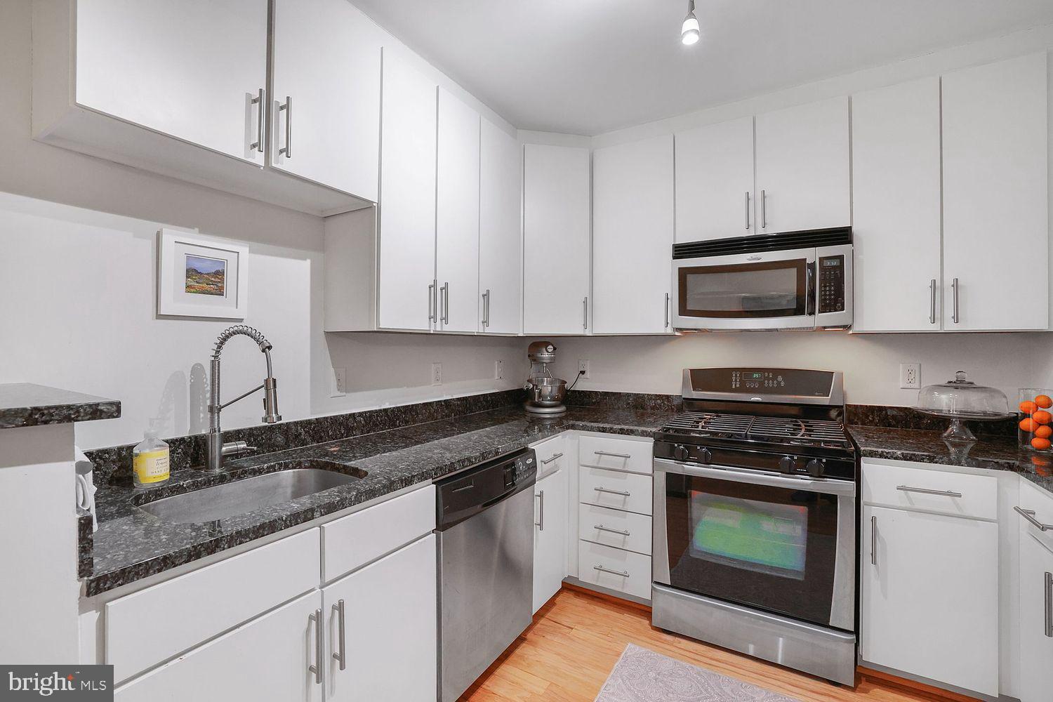 915 E Street Northwest, Unit 403 Washington, DC 20004 - Photo 10 of 30 a kitchen with granite countertop white cabinets and stainless steel appliances