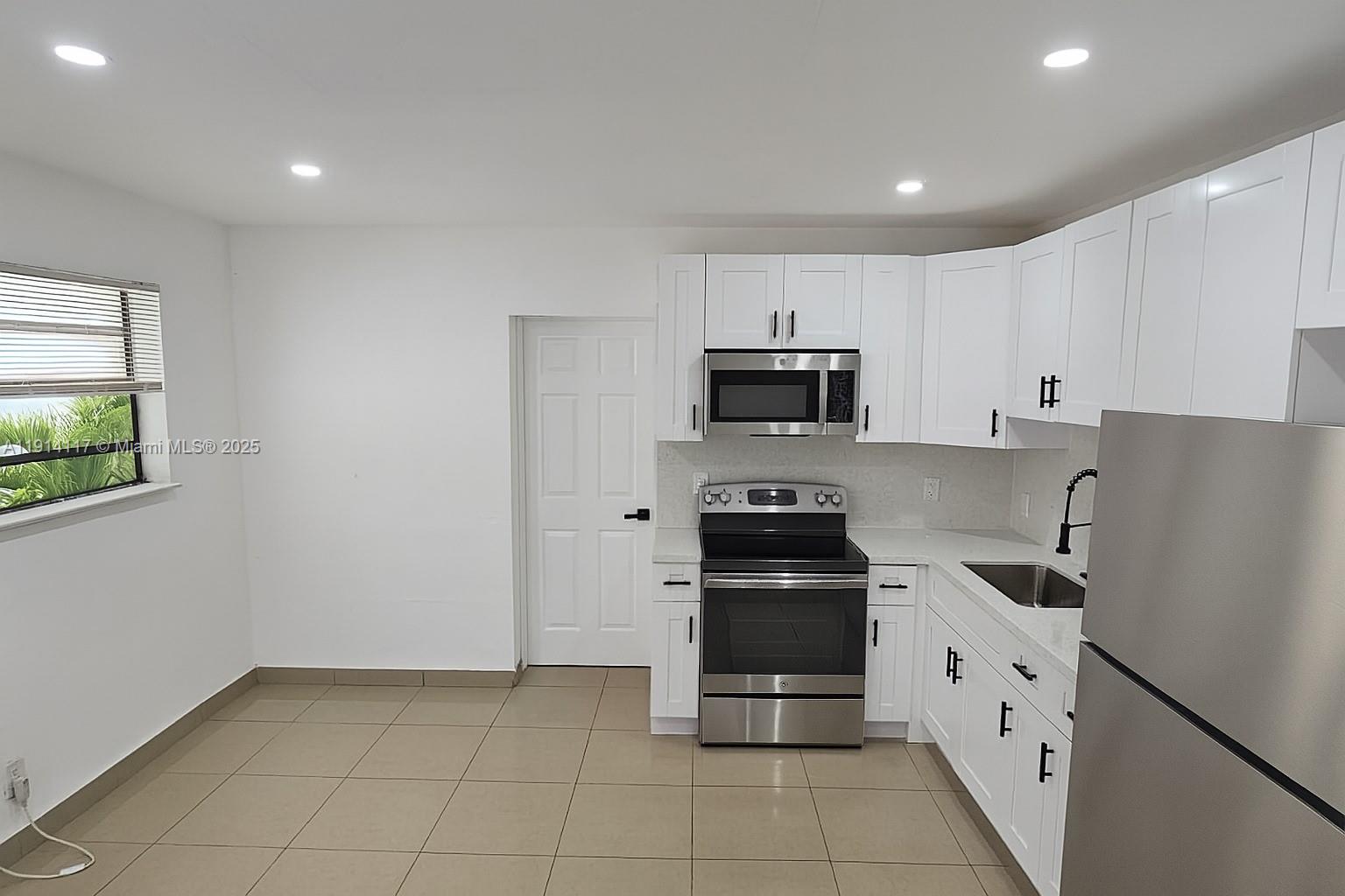 a kitchen with white cabinets and appliances