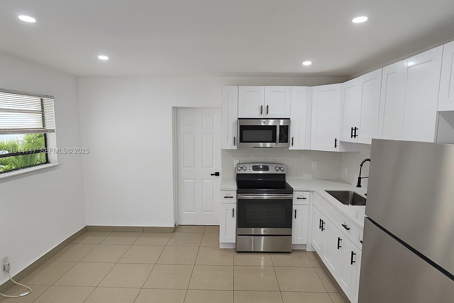 1046 Foster Road, Unit 1 Hallandale Beach, FL 33009 - Photo 2 of 8 a kitchen with white cabinets and appliances