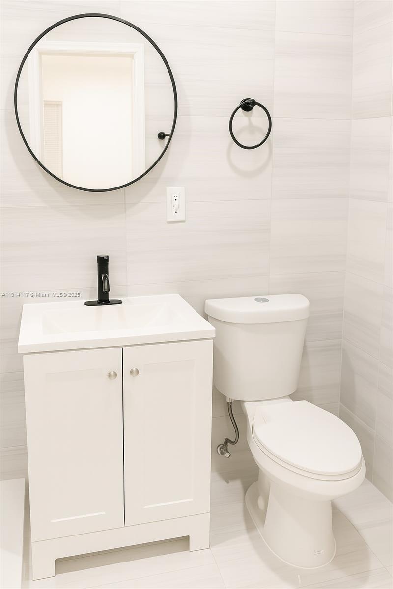 1046 Foster Road, Unit 1 Hallandale Beach, FL 33009 - Photo 6 of 8 a bathroom with a sink a toilet and a mirror