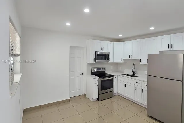 a kitchen with stainless steel appliances granite countertop white cabinets a stove a sink and dishwasher