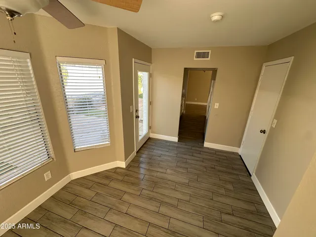 a view of an empty room with wooden floor and a window