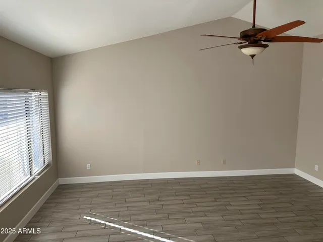 a view of a room with wooden floor a ceiling fan and window