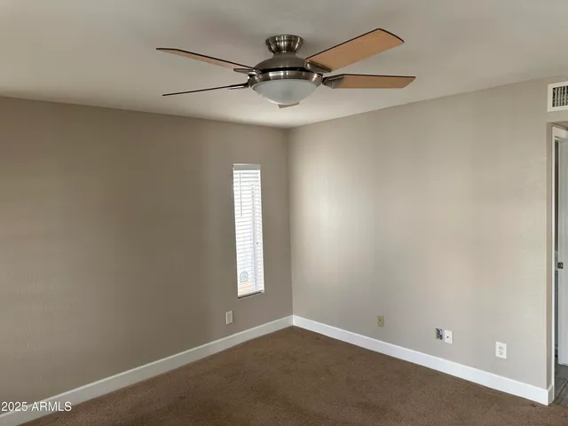 an empty room with windows and fan