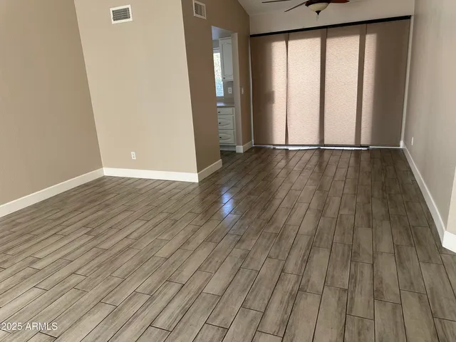 a view of empty room with wooden floor and fan