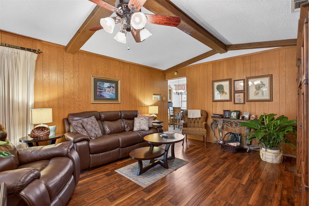 6010 Hunters View Lane Dallas, TX 75232 - Photo 12 of 28 Living space featuring wood-finish flooring, wood-paneled walls, and a white ceiling with exposed wood beams