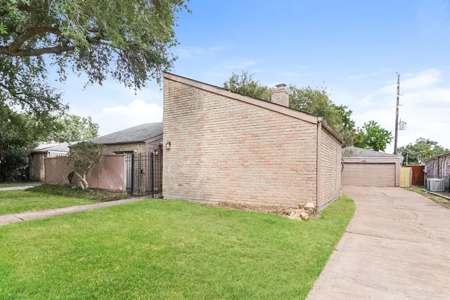 a backyard of a house with plants and large tree