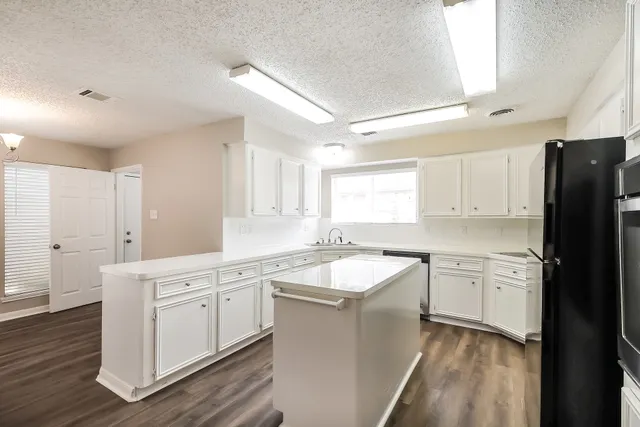 a kitchen with granite countertop white cabinets white appliances with wooden floor