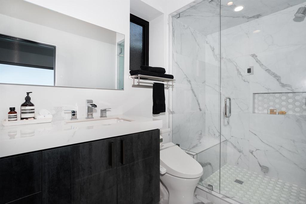 1095 Hoover Street Carlsbad, CA 92008 - Photo 59 of 75 a bathroom with a sink a toilet a mirror and shower