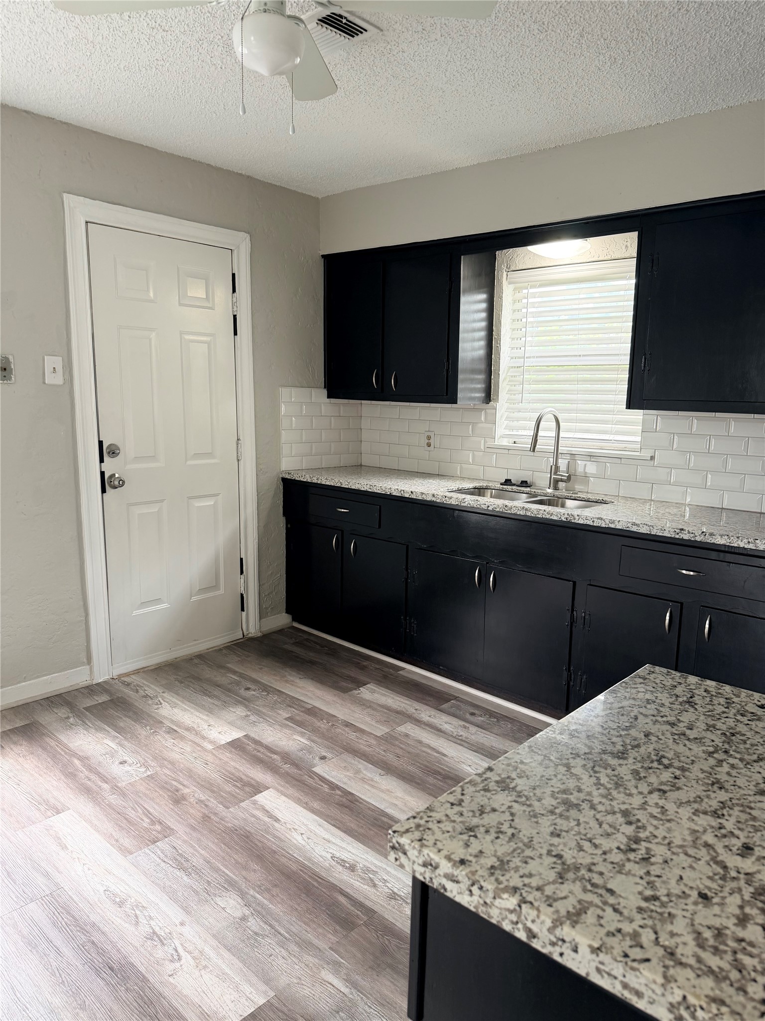 5003 Terry Street Houston, TX 77009 - Photo 9 of 21 Bright kitchen space with window over sink overlooking the backyard. Granite countertops and white subway tile backsplash. The side door allows additional access to outdoor spaces.