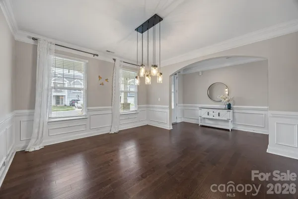 a view of a livingroom with wooden floor a ceiling fan and windows