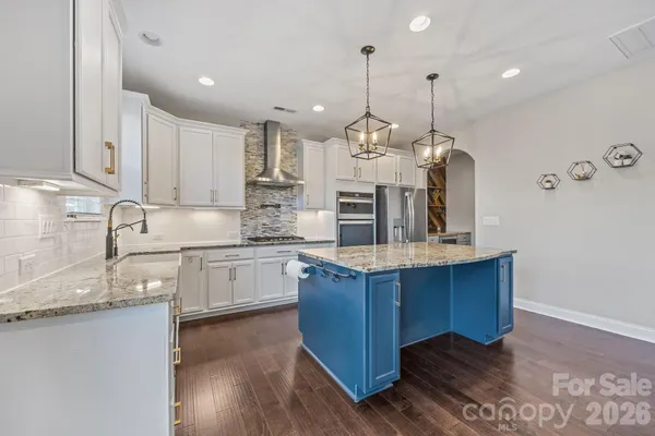 a kitchen with stainless steel appliances granite countertop a sink a stove a refrigerator and a oven with wooden floor