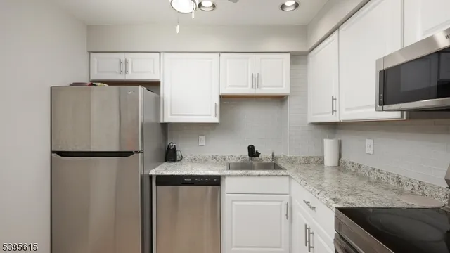 a kitchen with stainless steel appliances granite countertop a refrigerator sink and microwave