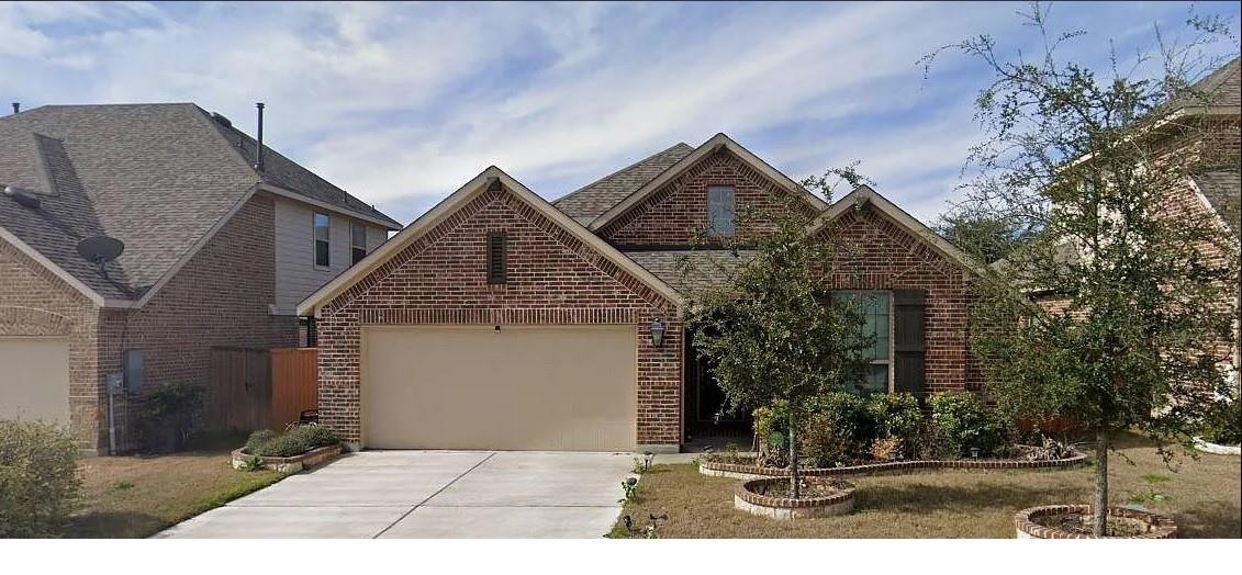 View of front of home featuring an attached garage, concrete driveway, and brick siding
