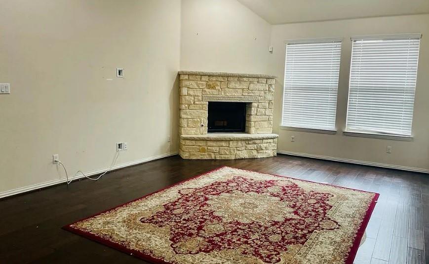 616 Garner Park Drive Georgetown, TX 78628 - Photo 3 of 26 Unfurnished living room featuring a fireplace, dark wood-style floors, and vaulted ceiling