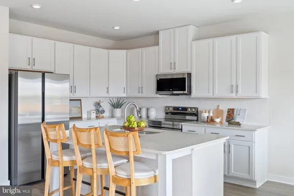 a kitchen with stainless steel appliances granite countertop a sink a stove a microwave a refrigerator and white cabinets