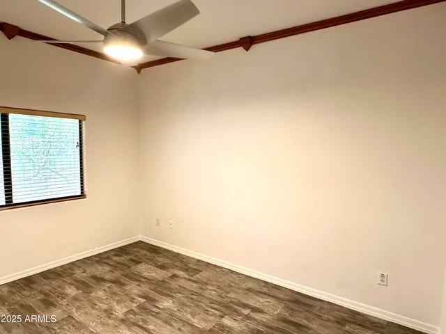 a view of empty room with wooden floor and fan