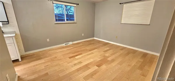 an empty room with wooden floor and windows