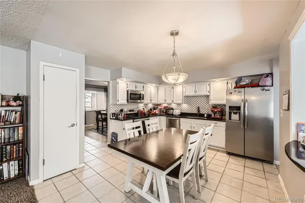 a kitchen with stainless steel appliances granite countertop a refrigerator a stove a sink a dining table and chairs