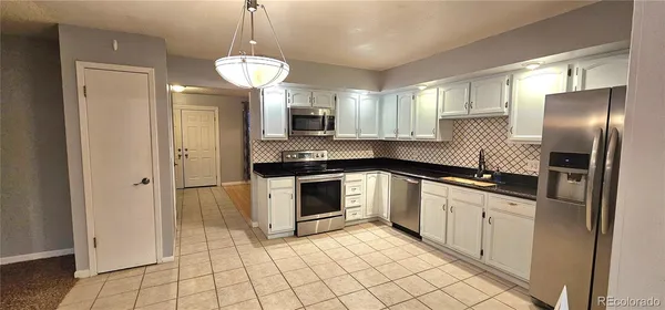 a kitchen with granite countertop white cabinets and stainless steel appliances