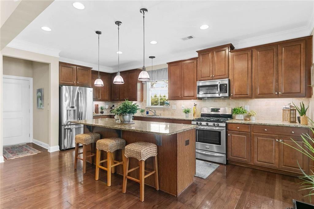 559 Bishopton Street Southeast Grayson, GA 30017 - Photo 14 of 34 a kitchen with stainless steel appliances granite countertop a stove a sink a refrigerator a microwave a dining table and chairs with wooden floor