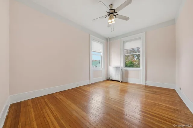 a view of an empty room with a window and wooden floor