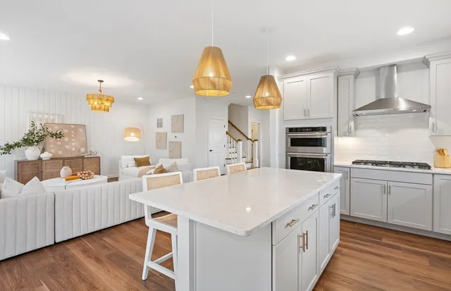 a large kitchen with kitchen island a stove a sink a refrigerator and white cabinets with wooden floor