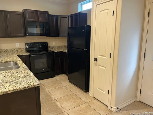 a kitchen with granite countertop wooden cabinets and refrigerator