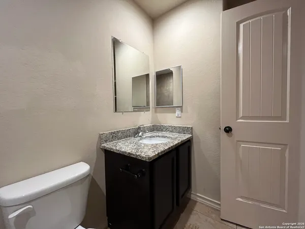 a bathroom with a granite countertop sink and a toilet