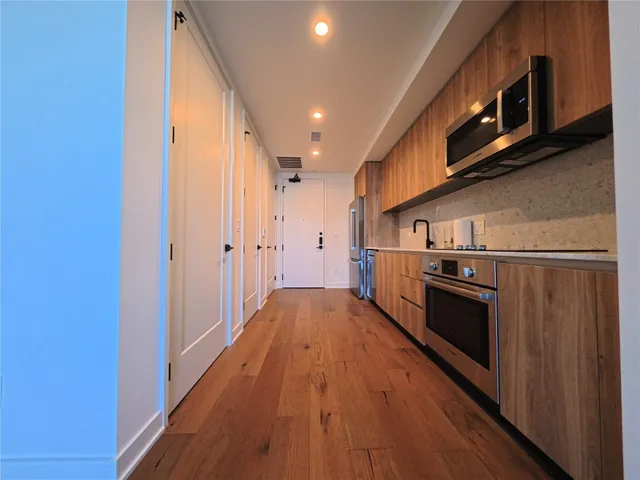 a view of a kitchen with stainless steel appliances granite countertop a refrigerator a stove top oven a sink and dishwasher