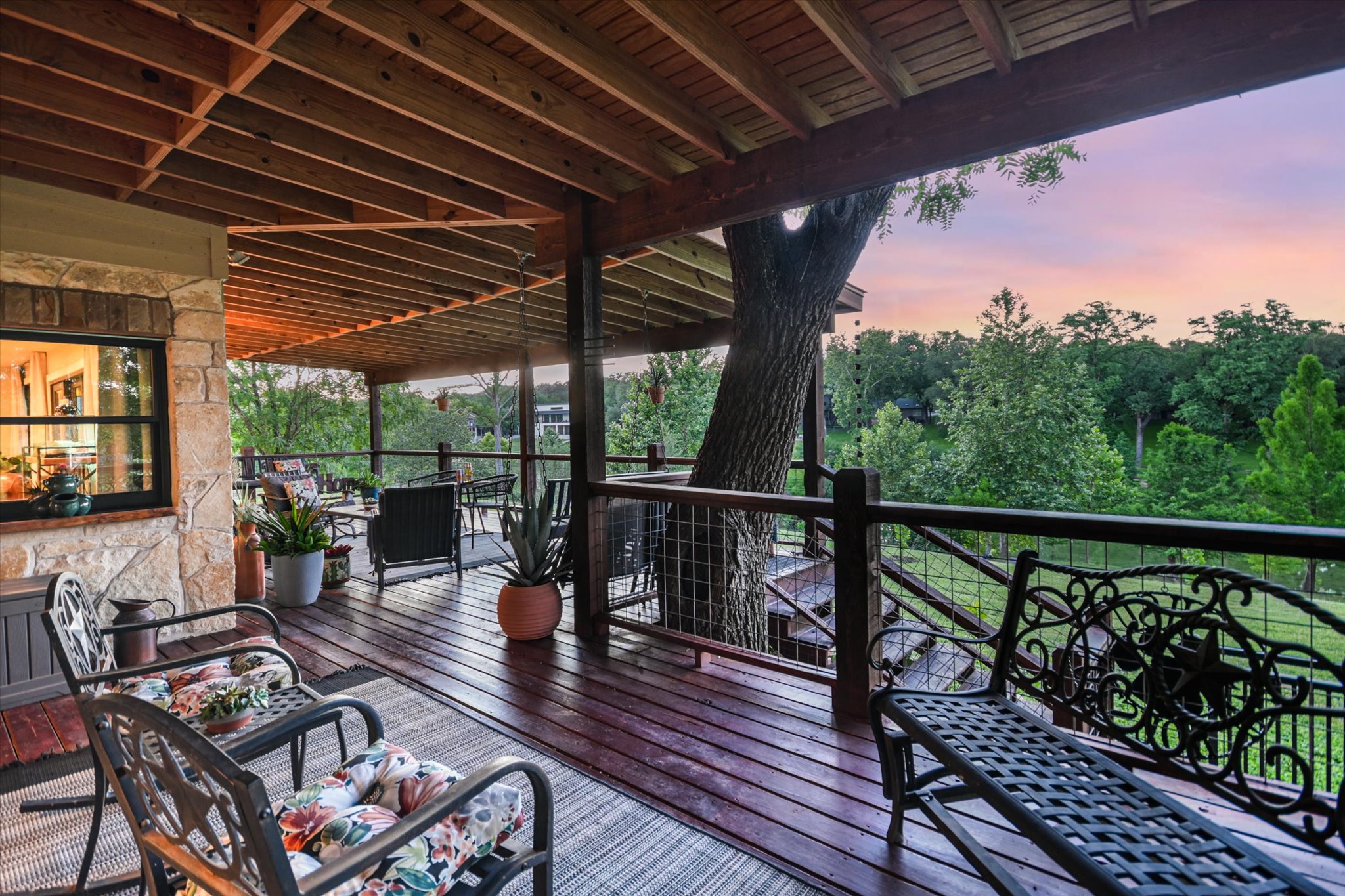 2411 Spoke Hollow Road Wimberley, TX 78676 - Photo 21 of 37 An inviting covered deck offers serene views of abundant trees under a painted sky.