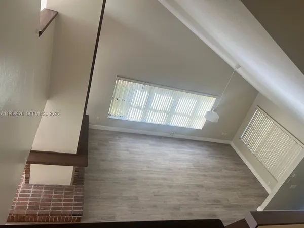 a view of an empty room and wooden floor and a window