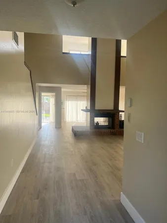 a view of a hallway to room with wooden floor