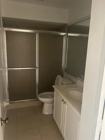 a view of a hallway with wooden floor and a bathroom