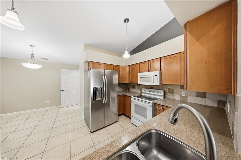 430 St Andrews Boulevard, Unit 6 Naples, FL 34113 - Photo 6 of 47 a kitchen with stainless steel appliances granite countertop a sink refrigerator and microwave