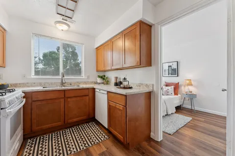 a kitchen with stainless steel appliances granite countertop a stove a sink dishwasher and wooden cabinets with wooden floor