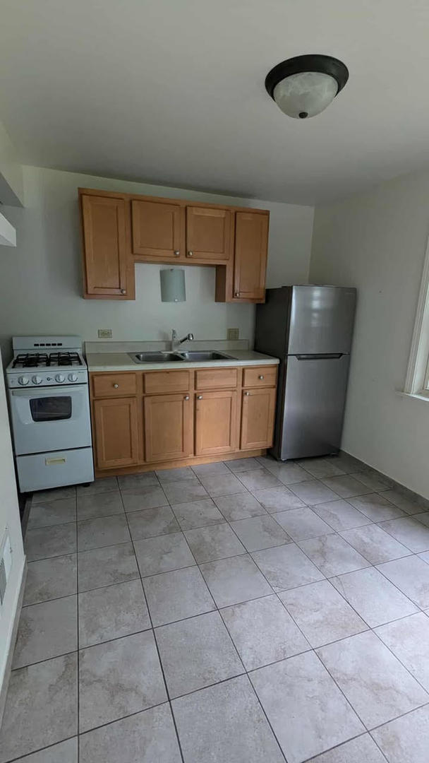 714 Glen Rock Avenue, Unit 3 Waukegan, IL 60085 - Photo 3 of 4 a kitchen with a sink a stove top oven and cabinets