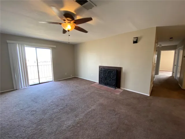 an empty room with windows and ceiling fan