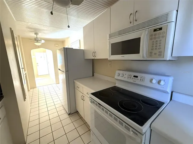 a hall with stainless steel appliances granite countertop a sink and a stove top oven