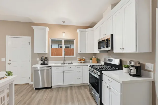 a kitchen with stainless steel appliances a sink stove top oven and white cabinets