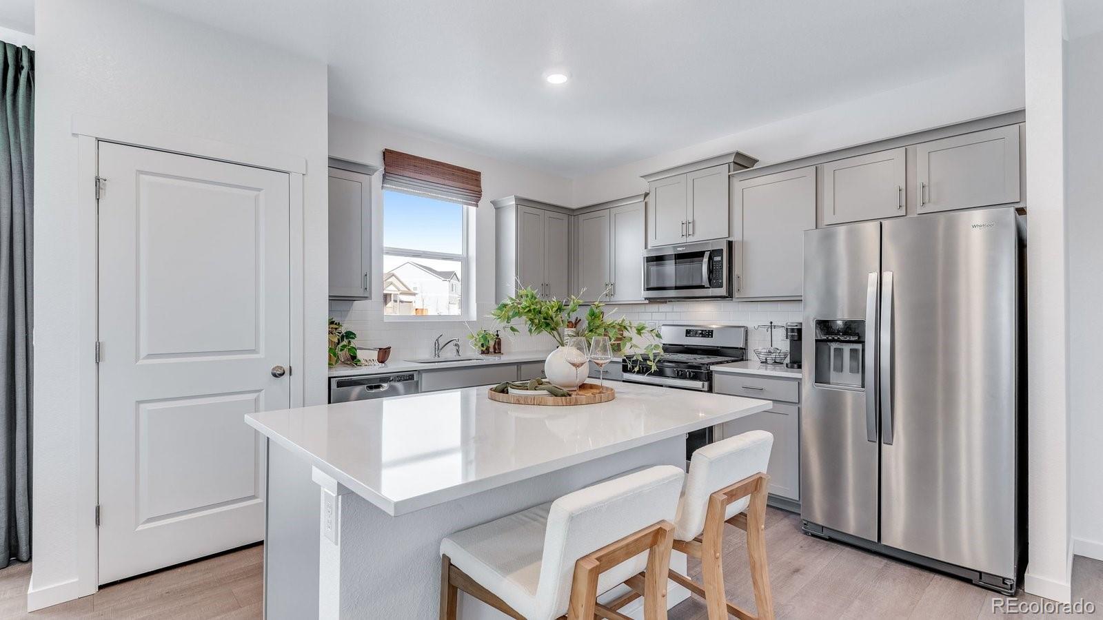 799 Ayrshire Road Johnstown, CO 80534 - Photo 11 of 36 a kitchen with a refrigerator a stove a sink and white cabinets