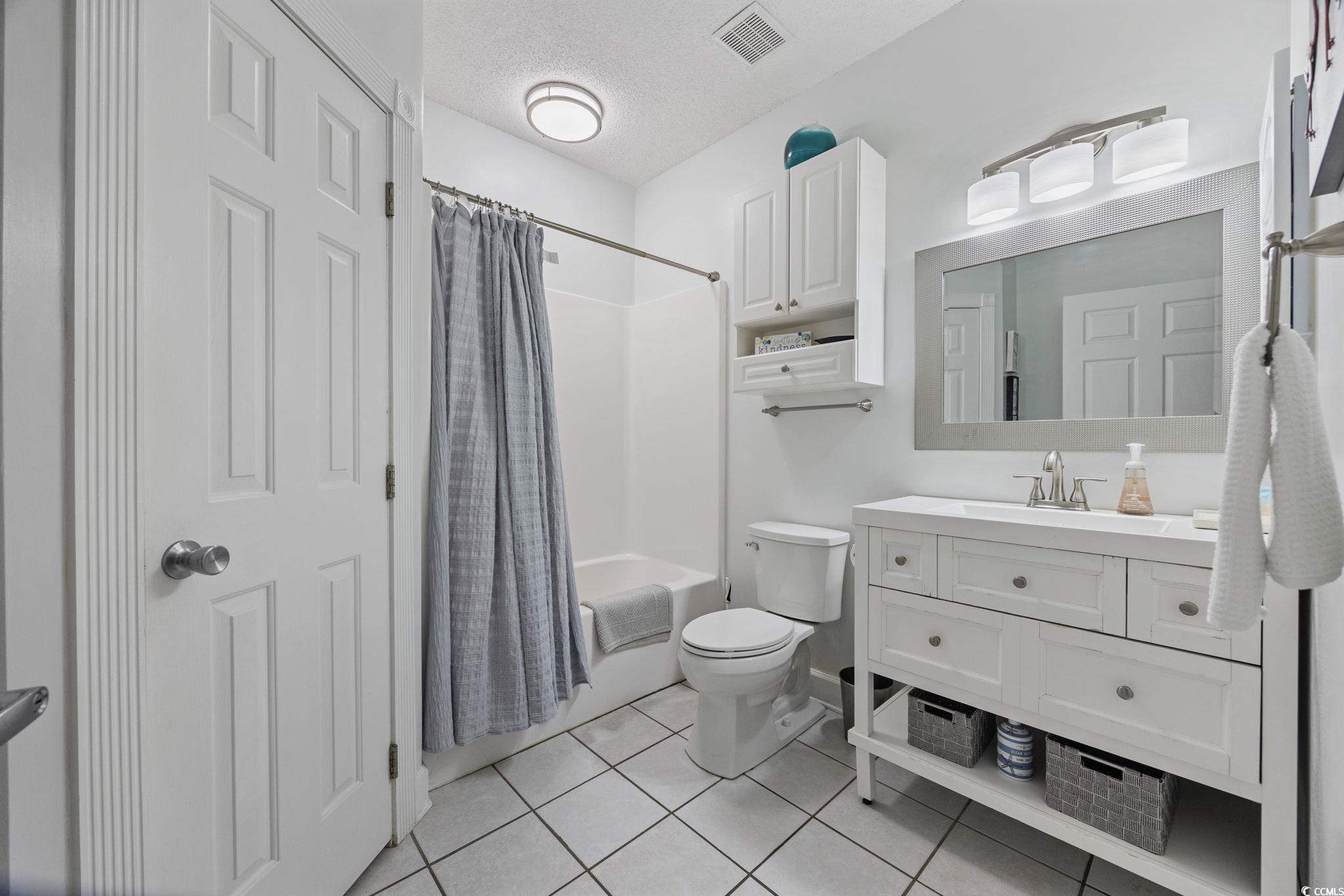 4846 Carnation Circle, Unit 103 Myrtle Beach, SC 29577 - Photo 16 of 31 Bathroom featuring shower / tub combo, light tile patterned floors, vanity, and a textured ceiling