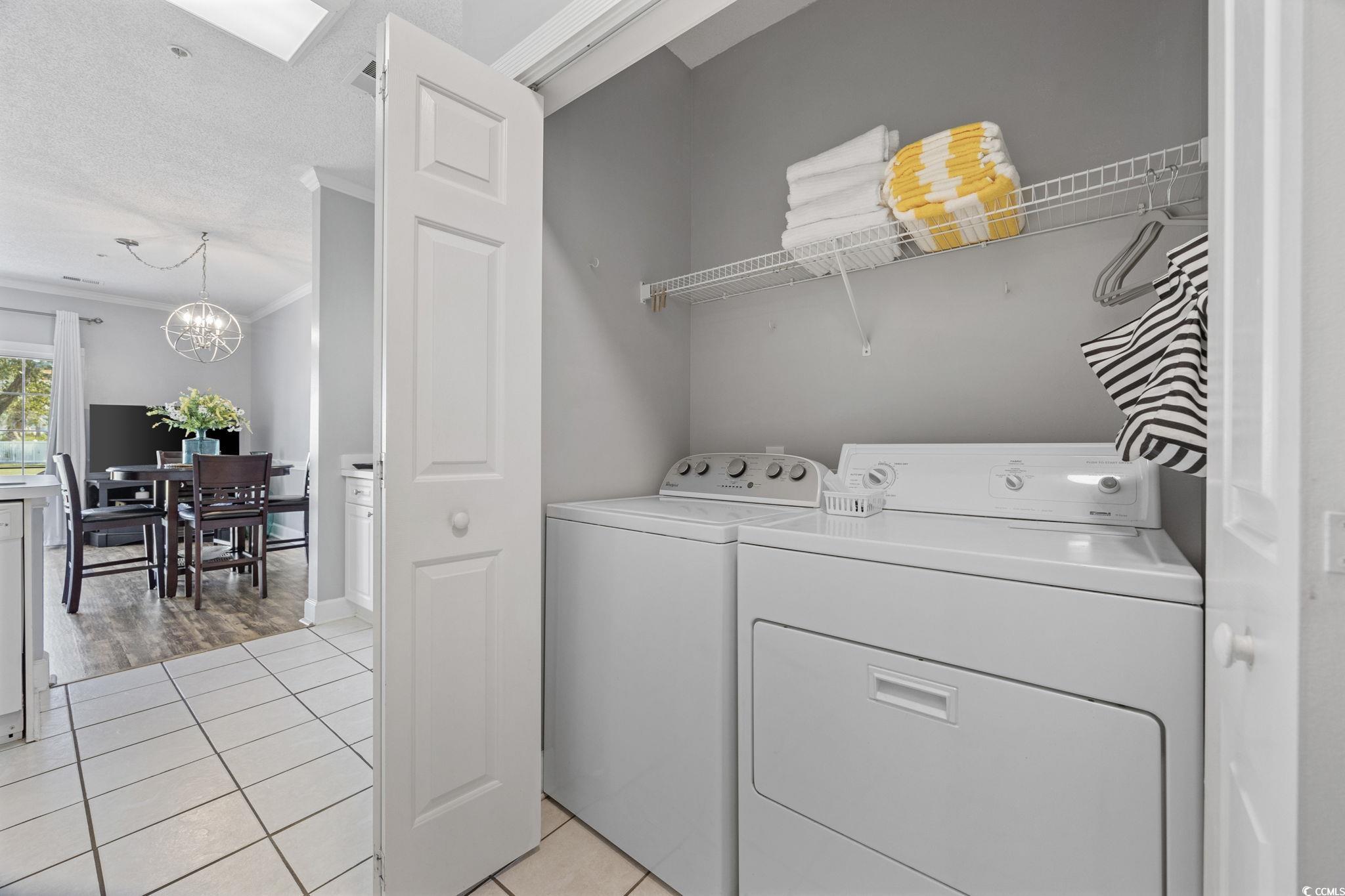 4846 Carnation Circle, Unit 103 Myrtle Beach, SC 29577 - Photo 4 of 31 Laundry area featuring light tile patterned floors, crown molding, washing machine and clothes dryer, a chandelier, and a textured ceiling