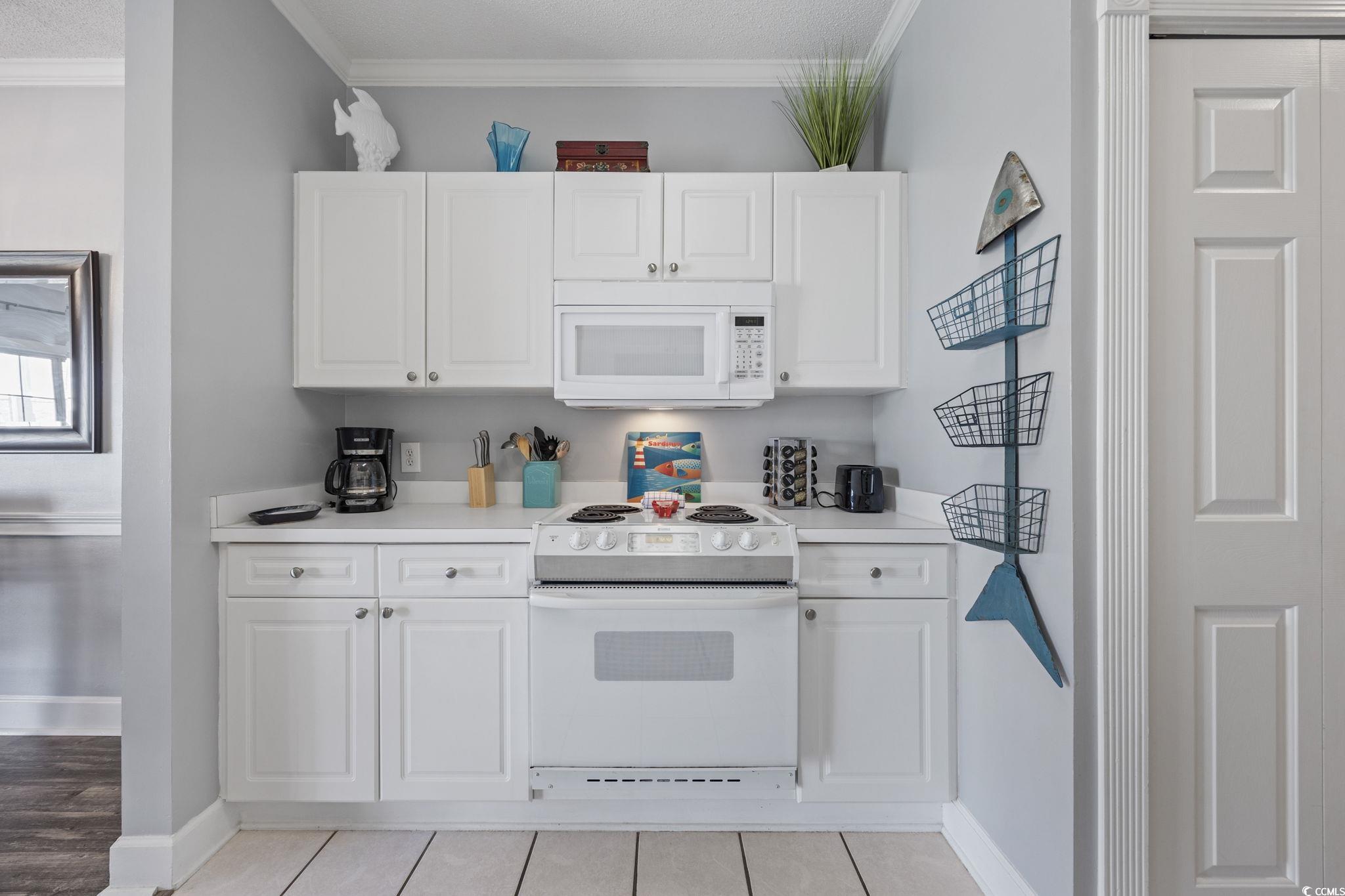 4846 Carnation Circle, Unit 103 Myrtle Beach, SC 29577 - Photo 7 of 31 Kitchen with light countertops, white appliances, ornamental molding, white cabinets, and light tile patterned floors