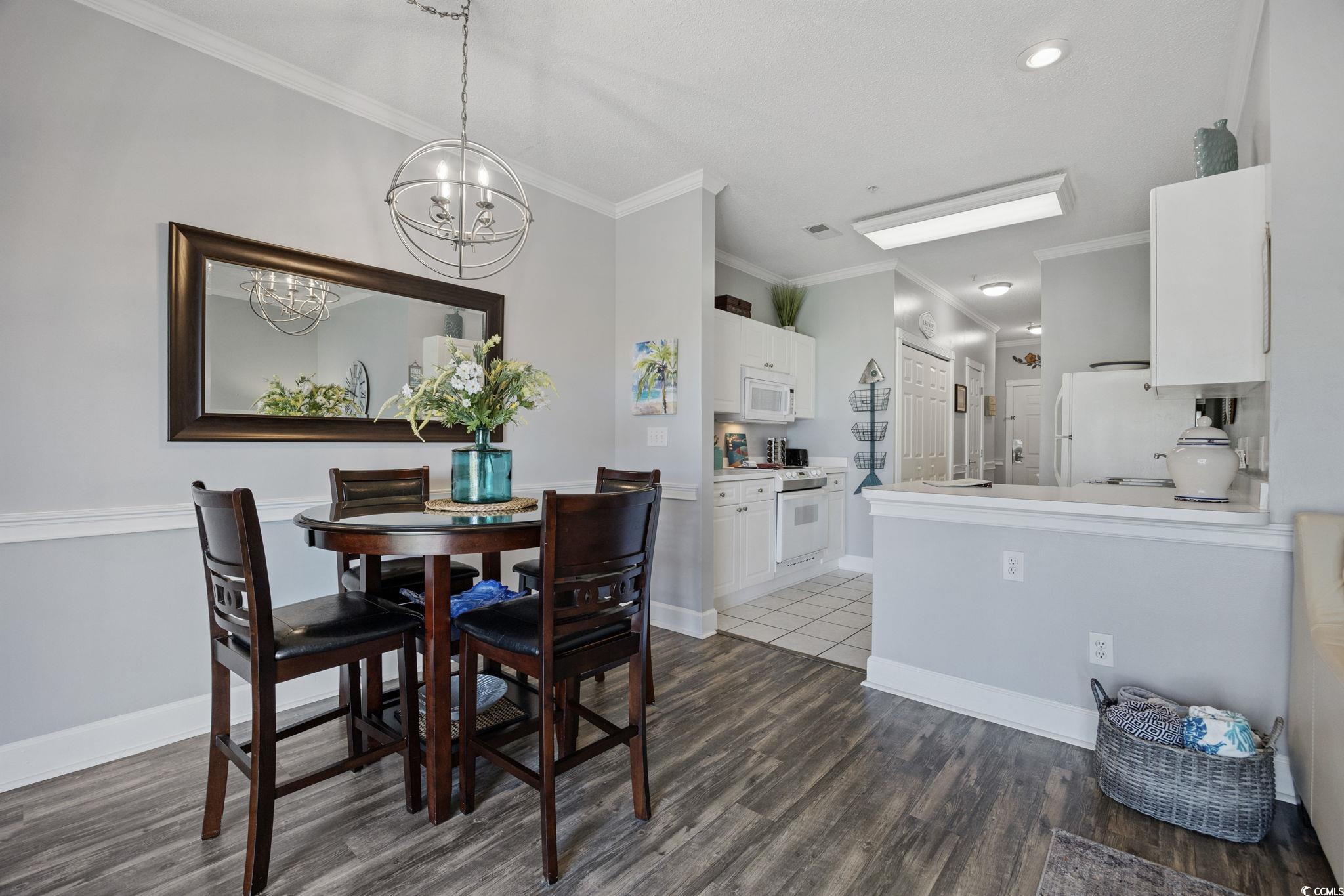 4846 Carnation Circle, Unit 103 Myrtle Beach, SC 29577 - Photo 10 of 31 Dining area with crown molding, dark wood finished floors, and a chandelier