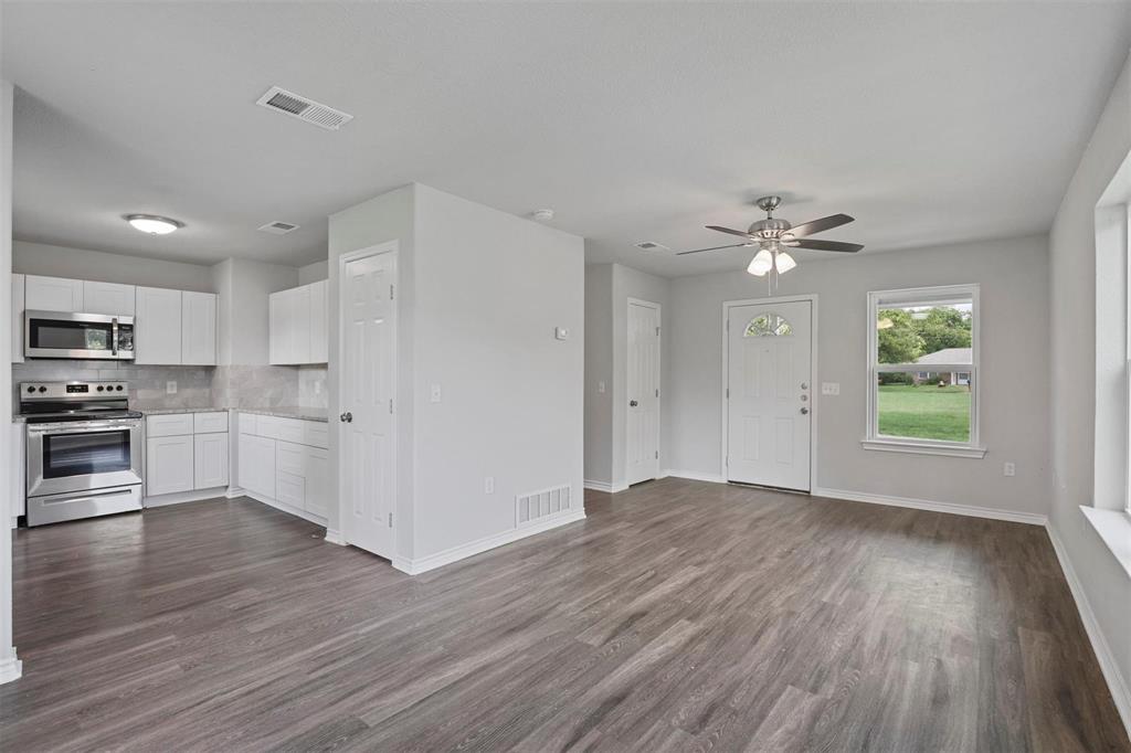 317 Jones Street Bonham, TX 75418 - Photo 3 of 15 Kitchen with white cabinets, stainless steel appliances, decorative backsplash, dark wood-style floors, and ceiling fan
