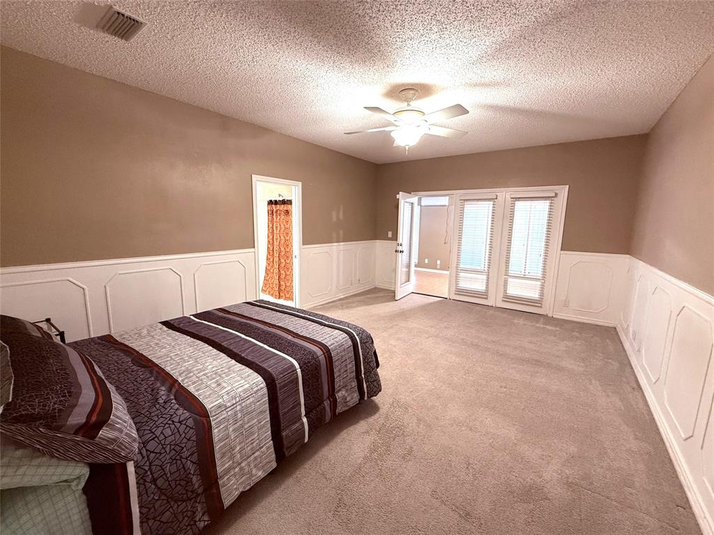 12098 Squirrel Road Pittsburg, TX 75686 - Photo 18 of 37 a bedroom with a large bed and a chandelier