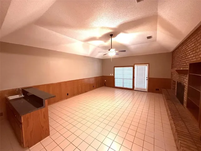 a view of kitchen and empty room with wooden floor