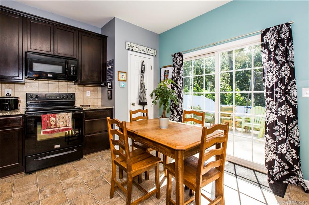 1621 Beleek Ridge Lane Clover, SC 29710 - Photo 14 of 24 a kitchen with stainless steel appliances granite countertop a stove a refrigerator a sink a dining table and chairs with wooden floor